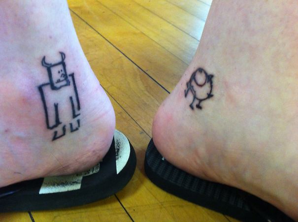 Pixar-inspired tattoos featuring minimalist monster designs on two ankles with flip-flops, on a wooden floor.