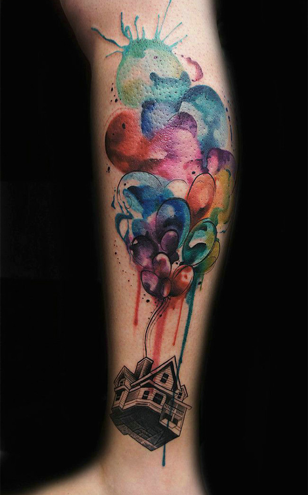 Colorful Pixar-inspired Up tattoo of a house with balloons on a leg, showcasing vibrant watercolor effects.