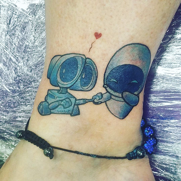 Pixar-inspired tattoo of two characters holding hands with a small heart above them, located on a person's ankle.