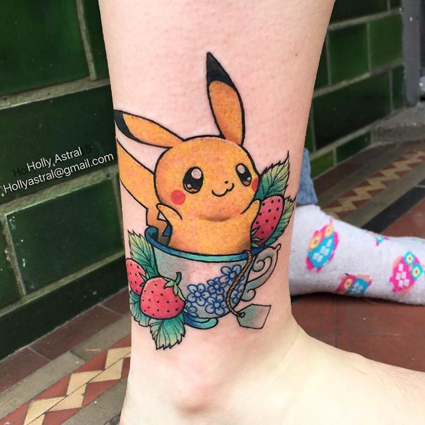 Pokemon tattoo featuring Pikachu in a teacup with strawberries, inked on a leg.