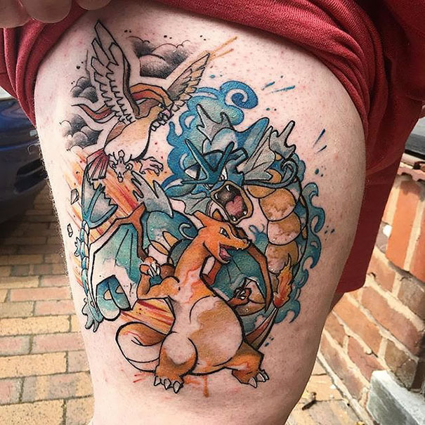Colorful Pokemon tattoo featuring Charizard, Gyarados, and Ho-Oh on the thigh of a fan.