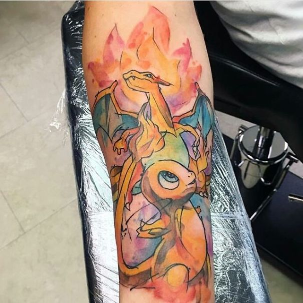 Colorful Pokemon tattoo featuring Charizard and Charmander on a person's forearm.