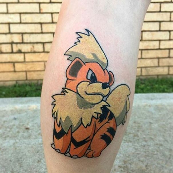 Pokemon tattoo featuring Growlithe on a person's leg against a brick wall background.