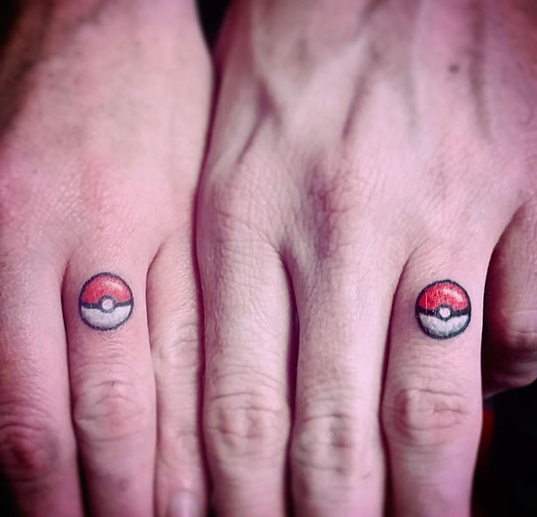 Hands with Pokeball tattoos on fingers, showcasing a minimalist Pokemon tattoo design.