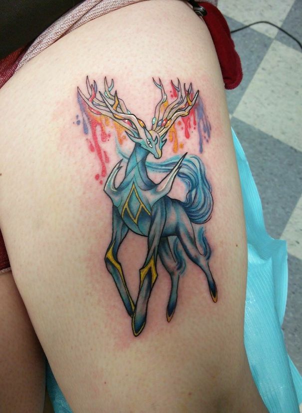 Colorful Pokemon tattoo of a majestic creature with antlers on skin.