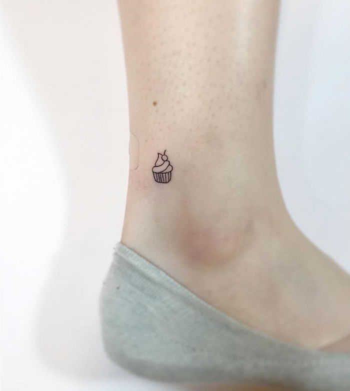 Minimalist tattoo of a small cupcake on an ankle.