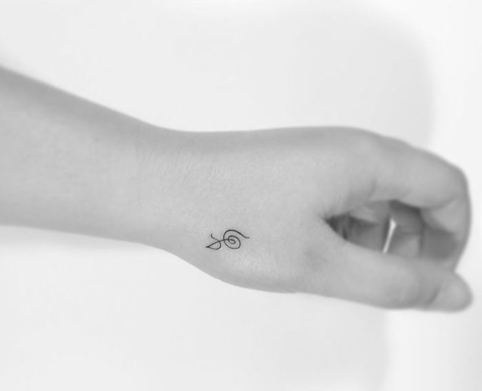Minimalist tattoo of a small snail design on wrist, created by a Korean artist.