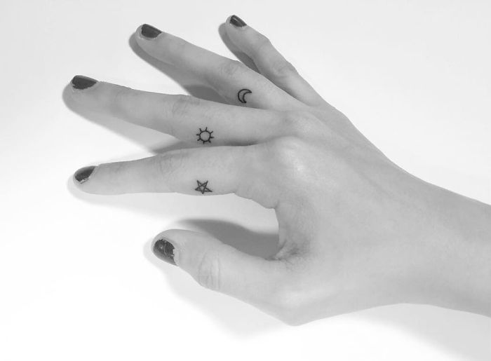 Minimalist tattoos of a sun, star, and crescent moon on fingers, designed by a Korean artist.