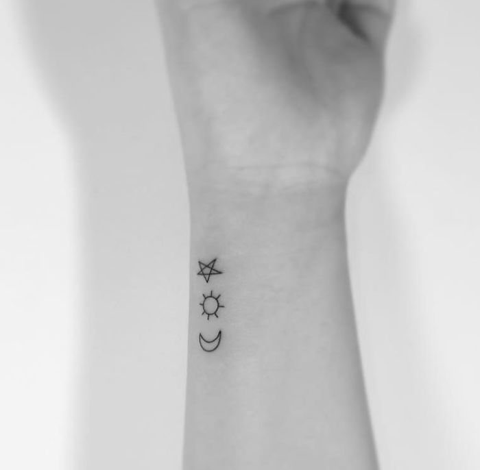 Minimalist tattoos on wrist by Korean artist featuring star, sun, and moon designs.