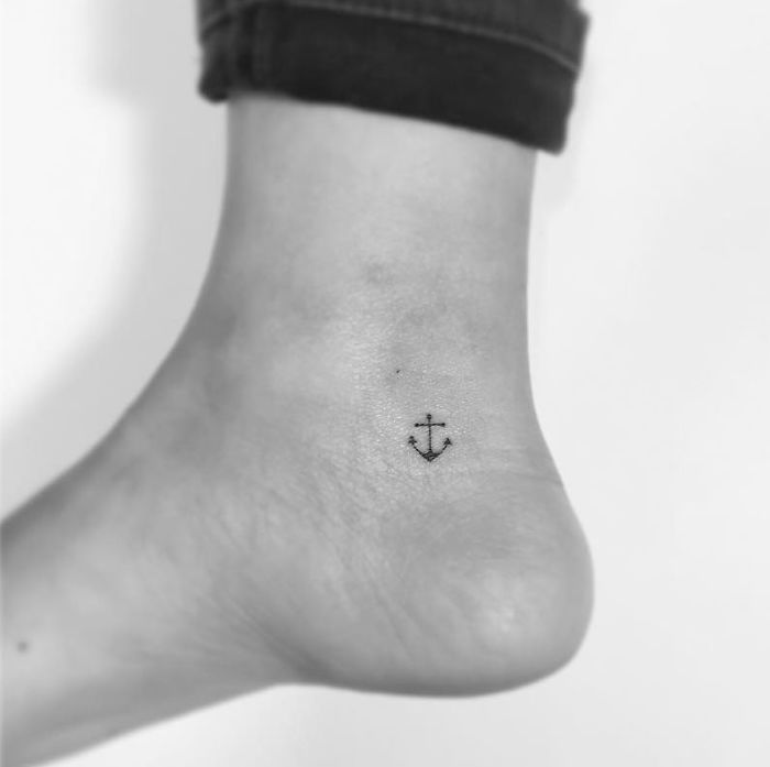 Minimalist tattoo of a small anchor on an ankle by a Korean artist.