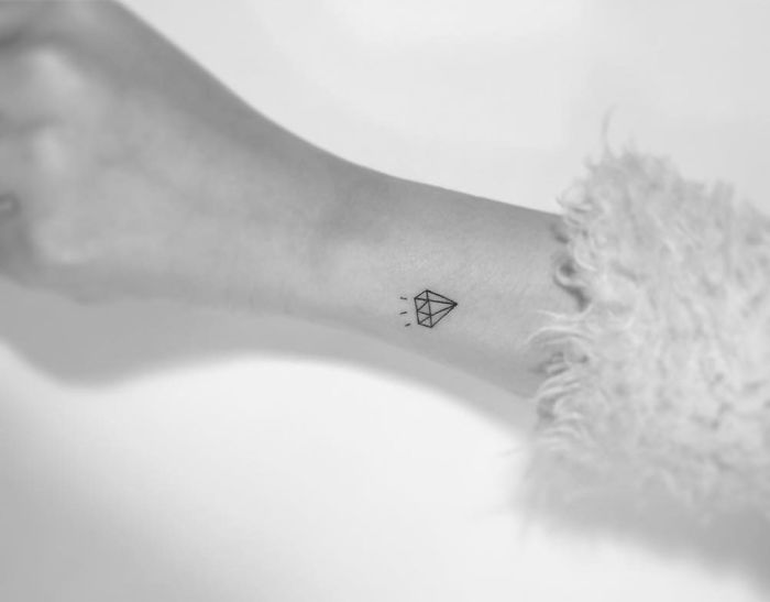 Minimalist tattoo of a diamond shape on a person's wrist designed by a Korean artist.