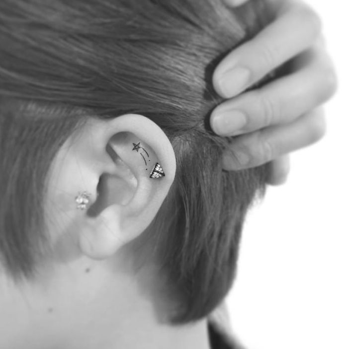 Minimalist tattoo of a shooting star and moon inside ear, designed by a Korean artist.