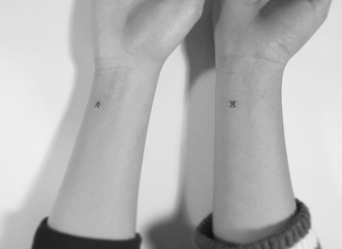 Minimalist tattoos on wrists by Korean artist, featuring small geometric designs.