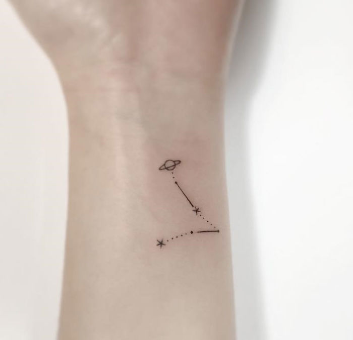 Minimalist tattoo of a constellation and planet on an inner wrist, designed by a Korean artist.
