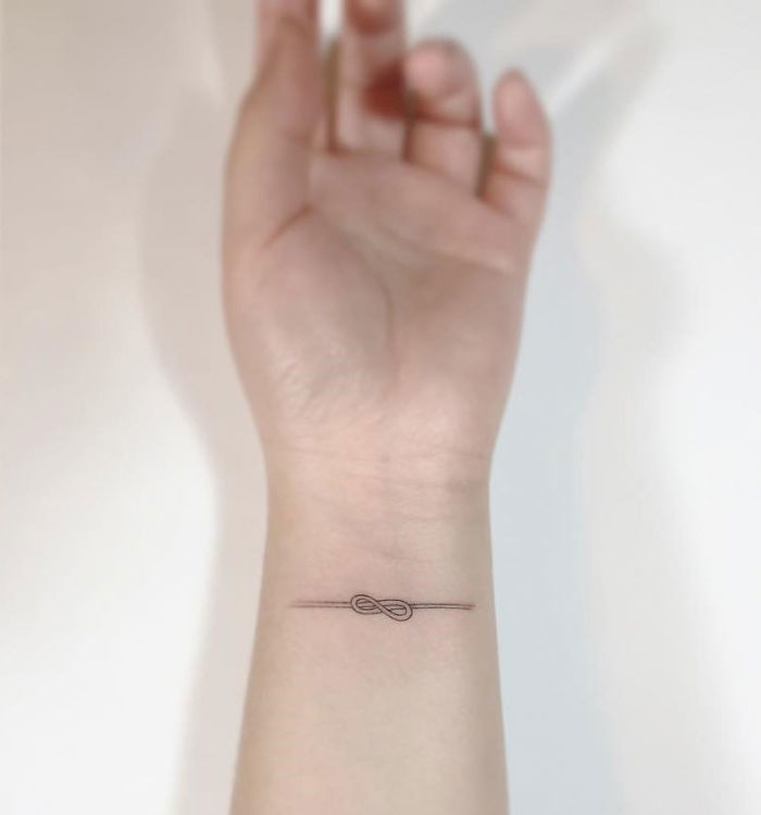 Minimalist tattoo on a wrist with a small infinity design by a Korean artist.