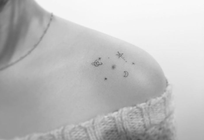 Minimalist tattoo of celestial elements on shoulder by Korean artist.