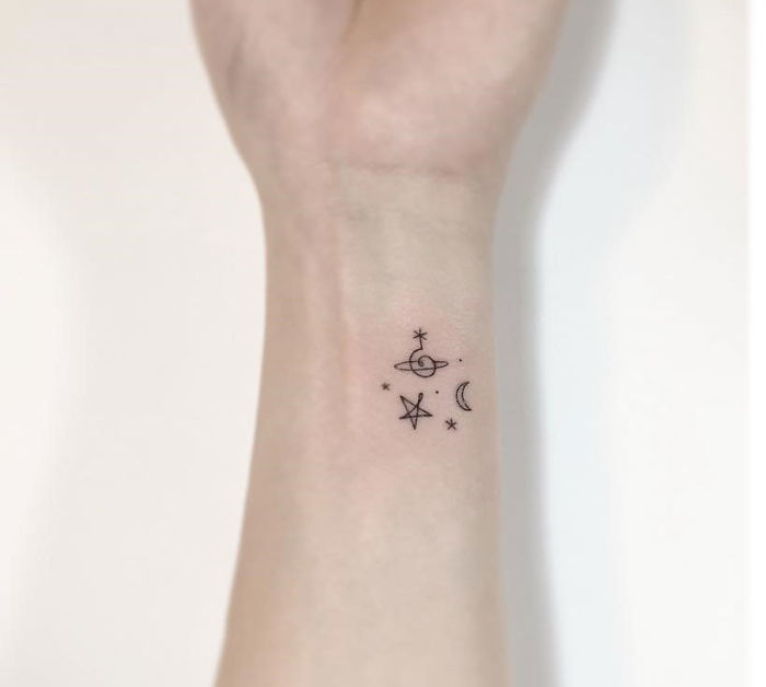 Minimalist tattoo on wrist featuring a star, moon, and planet design by a Korean artist.