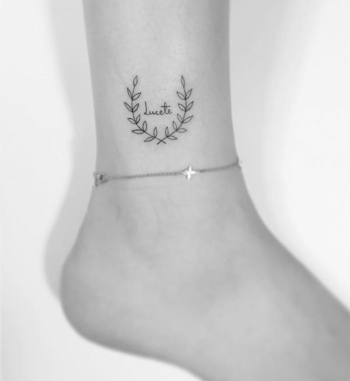 Minimalist tattoo of a wreath on an ankle by a Korean artist, paired with a delicate ankle bracelet.