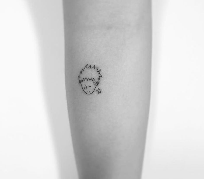 Minimalist tattoo of a simple face and star on a forearm by a Korean artist.