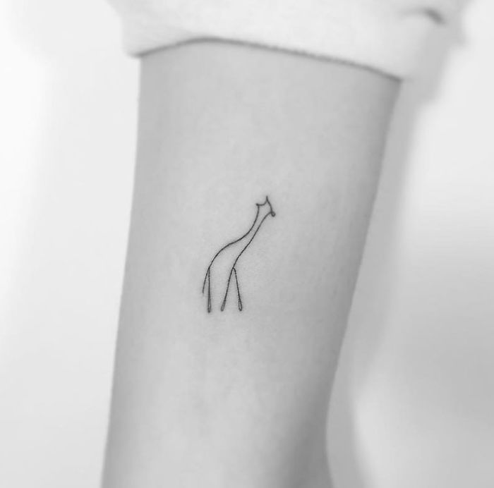 Minimalist tattoo of a giraffe on an arm by a Korean artist.