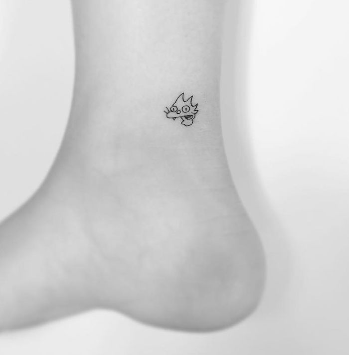 Minimalist tattoo of a small dragon on an ankle, designed by a Korean artist.