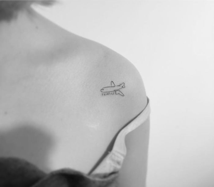 Minimalist tattoo of an airplane design on a person's shoulder by a Korean artist.