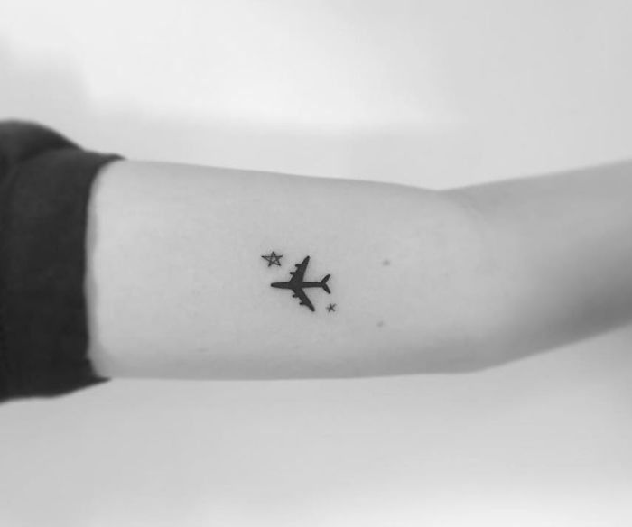 Minimalist tattoo of a plane with stars on an arm, designed by a Korean artist.
