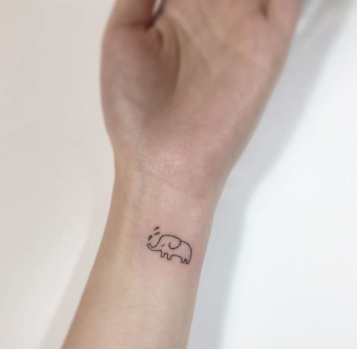 Minimalist tattoo of an elephant on a wrist by a Korean artist.