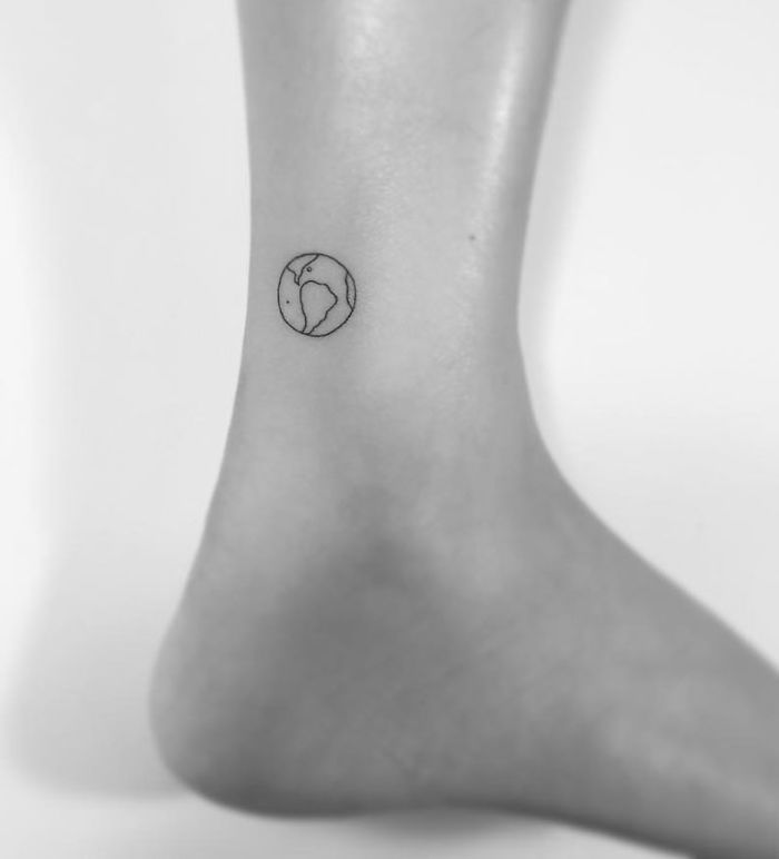 Minimalist tattoo of Earth on the ankle, created by a Korean artist.