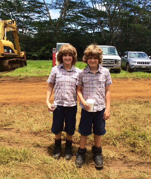 Two boys wearing matching outfits stand outdoors holding drinks, illustrating celebrity body doubles in Hollywood.