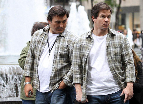 Two men in matching plaid shirts and white tees walking near a fountain, showcasing Hollywood celebrity body doubles.