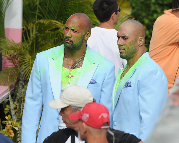 Two men dressed alike in light blue suits covered in green powder, showcasing Hollywood celebrities’ body doubles in action.