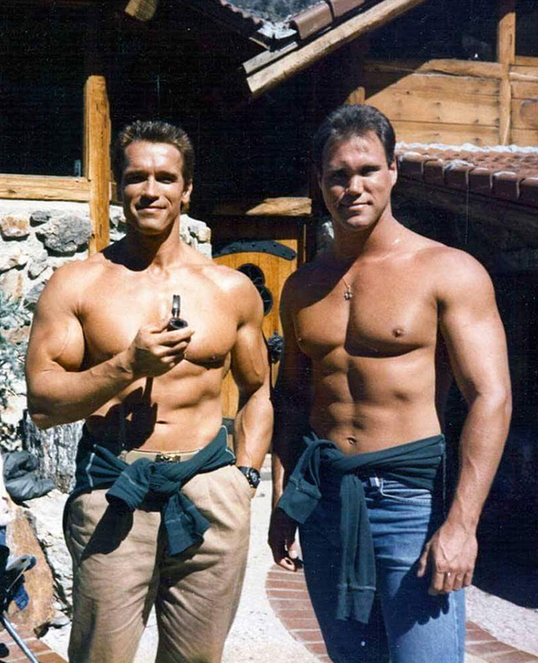 Two muscular men shirtless outside a wooden cabin, illustrating Hollywood fooled us with celebrities’ body doubles.