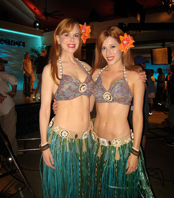Two women dressed as Hawaiian dancers showcasing Hollywood celebrities body doubles in a studio setting.