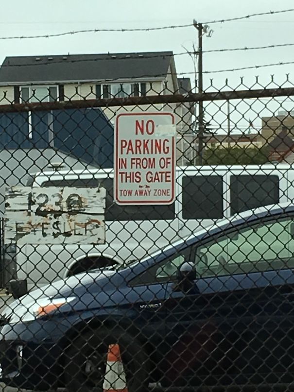 Failed job example: Sign reads "No Parking in From of This Gate," seen behind a fence with parked cars.