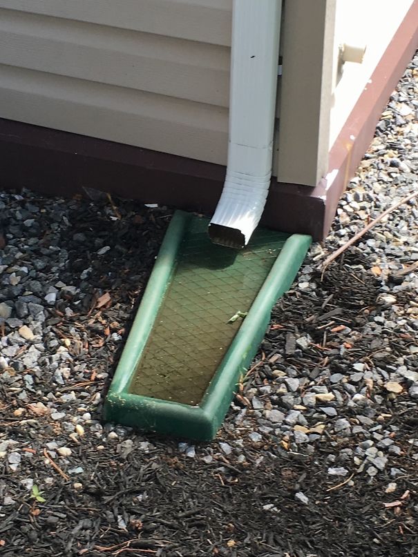 Downspout misaligned, water pooling ineffectively on gravel, highlighting a job fail.