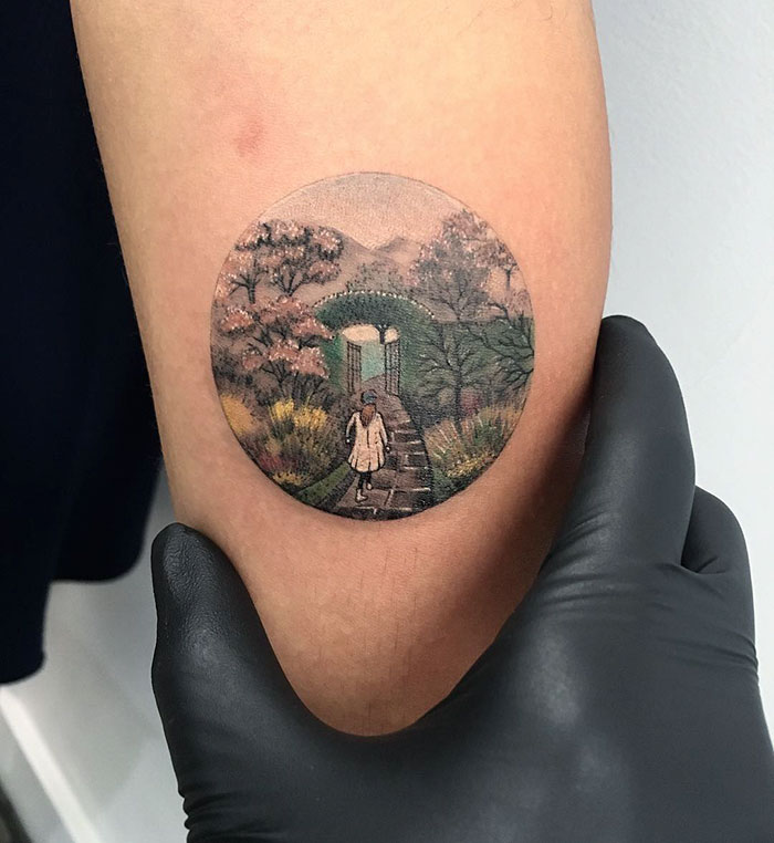 Close-up of a miniature circle tattoo by a Turkish artist, depicting a scenic pathway on an arm.
