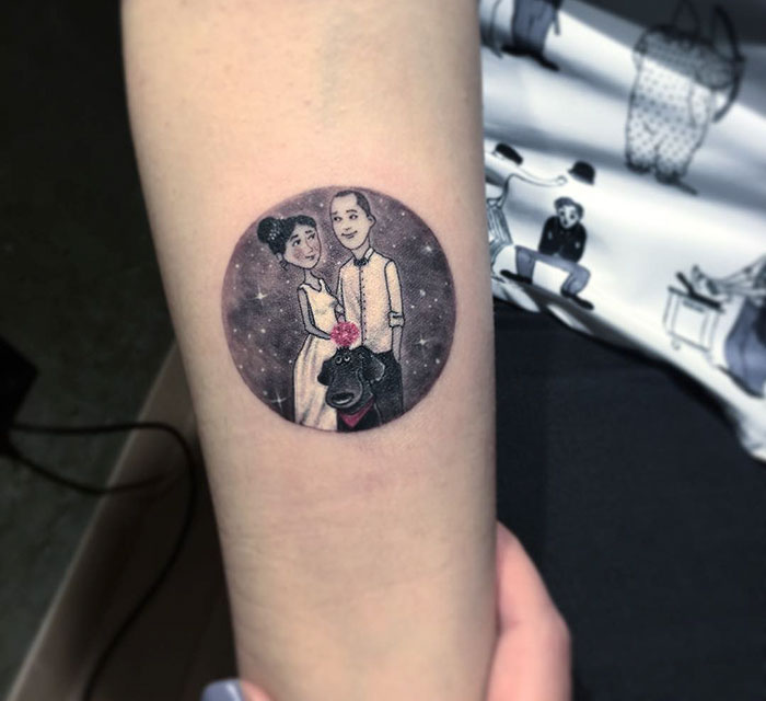 Miniature circle tattoo of a couple and a dog, designed by Turkish artist Eva Krbdk, inked on a person's forearm.
