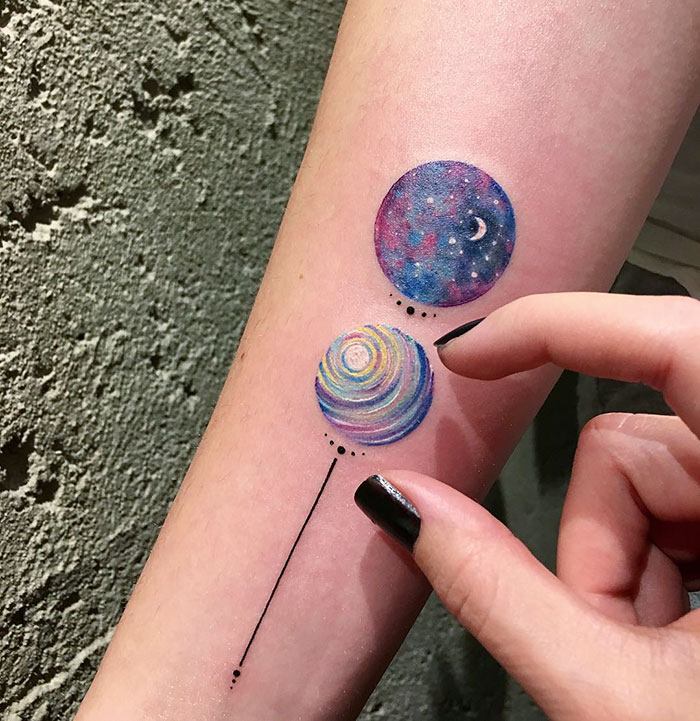 Miniature circle tattoos with cosmic and colorful designs on arm by Turkish artist Eva Krbdk.