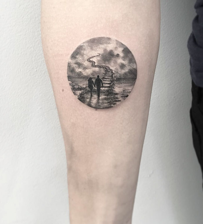 Miniature circle tattoo depicting a scenic path with two people by Turkish artist Eva Krbdk.