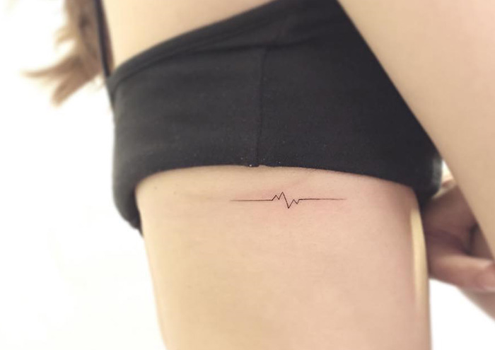 Minimalist tattoo of a heartbeat line on a person's side, designed by a Korean artist.