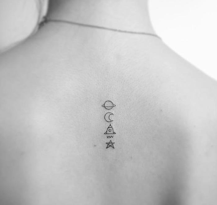 Minimalist tattoo by Korean artist featuring planet, moon, triangle, waves, and star symbols on a person's back.