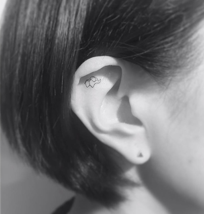 Minimalist tattoo of a small elephant inside a person's ear by Korean artist.