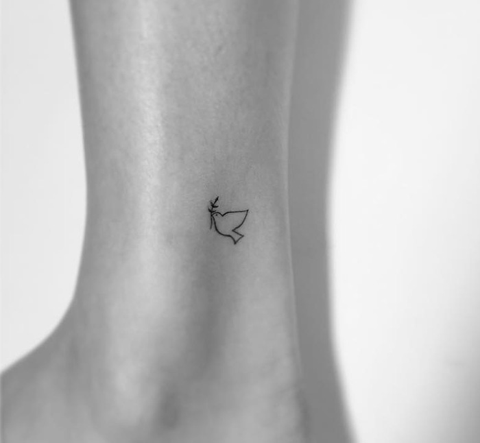Minimalist tattoo of a small bird on an ankle, designed by a Korean artist.