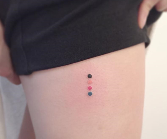 Four minimalist dots tattooed on skin, designed by Korean artist.