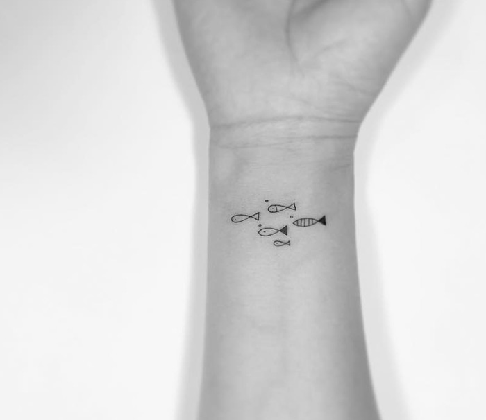 Minimalist tattoo of small fish design on a forearm, created by a Korean artist.