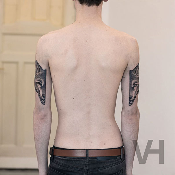 Back view of person with symmetrical tattoos of wolves on both arms, blending nature and geometry.