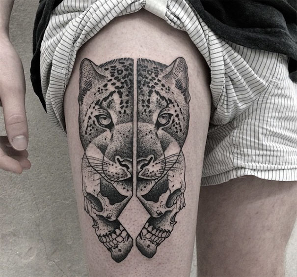 Symmetrical tattoo on thigh depicting a leopard face with geometric precision, blending nature and geometry.
