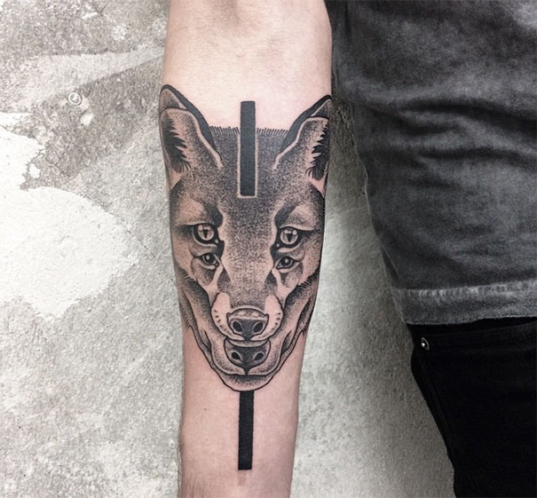 Symmetrical tattoo by Valentin Hirsch, featuring a geometric wolf design on an arm.