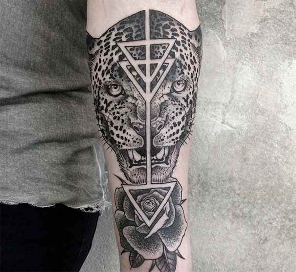Symmetrical tattoo on arm featuring a leopard face and geometric patterns, blending nature with geometry.